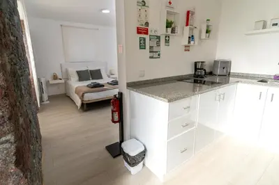 a kitchen with white cabinets and a bedroom with a bed at Villas Renacer in Paul do Mar