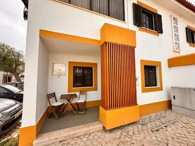 a house with orange and white walls and chairs at Casa da Ribeira in Vila do Bispo