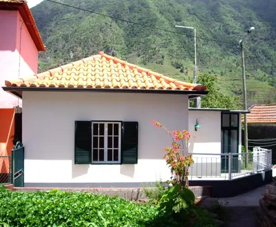a small white house with a mountain in the background at Holidays Madeira in São Vicente