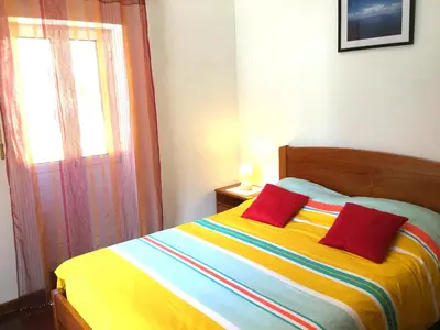 a bedroom with a bed with two red pillows and a window at Holidays Madeira in São Vicente