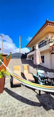 a hammock and an umbrella in front of a house at GuestReady - Quinta das Estrelas in Campanário