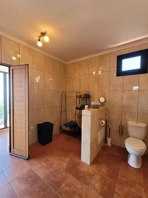 a bathroom with a toilet and a television on the wall at Sunset Paradise Villa with Heated Pool in Calheta