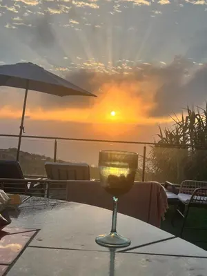 a glass of wine sitting on a table with the sunset at Sunset Paradise Villa with Heated Pool in Calheta