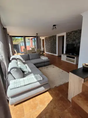 a living room with a couch and a television at Sunset Paradise Villa with Heated Pool in Calheta