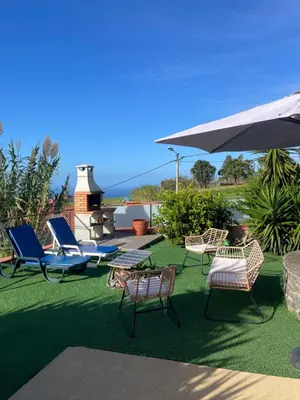 a group of chairs and an umbrella on a lawn at Sunset Paradise Villa with Heated Pool in Calheta