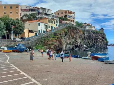 a group of people standing on a beach near the water at Maria's House in Câmara de Lobos