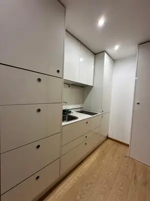 a white kitchen with white cabinets and a wooden floor at Living Funchal V in Funchal