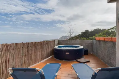 a hot tub sitting on a patio with chairs at Sa Dias House by AH in São Jorge