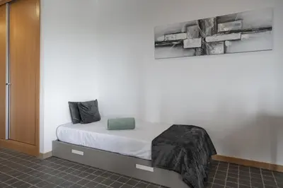 a bedroom with a bed with white sheets and green pillows at OurMadeira - VistaSerena in Raposeira do Logarinho
