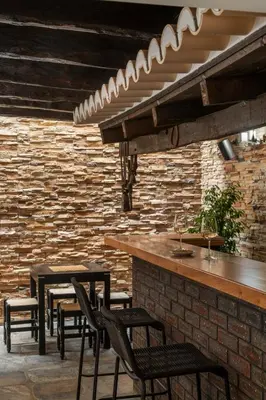 a bar with black chairs and a brick wall at Vila Esperança by An Island Apart in Calheta