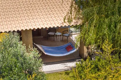 a hammock on a patio with a table and two chairs at Vila Esperança by An Island Apart in Calheta