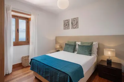 a bedroom with a large white bed with blue pillows at Vila Esperança by An Island Apart in Calheta