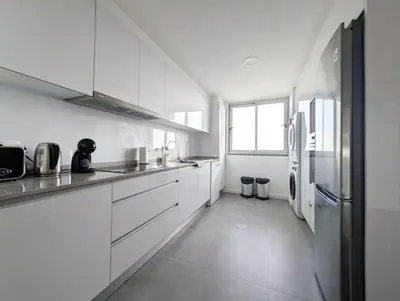 a white kitchen with white cabinets and a refrigerator at Seaview wonder apartment by Anna in Funchal
