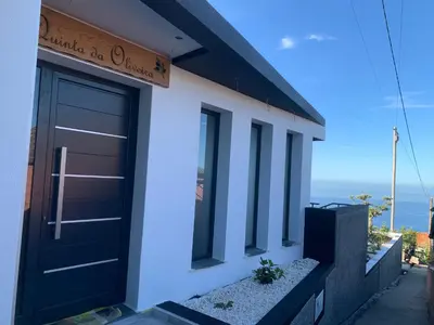 a black door on a building with the ocean in the background at Quinta da Oliveira in Ponta do Sol