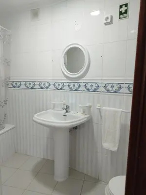 a white bathroom with a sink and a mirror at Alojamento Central II in Funchal