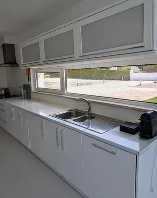 a white kitchen with a sink and a window at White Beach Villa in Sagres