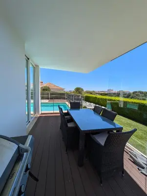 a deck with a table and chairs and a grill at White Beach Villa in Sagres