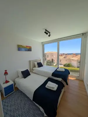 a bedroom with two beds and a large window at White Beach Villa in Sagres
