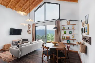 a living room with a table and a large window at Mountain Chalet by Lavibes in São Vicente