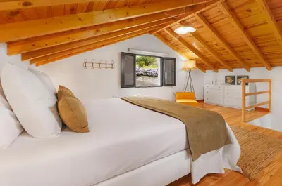 a large white bed in a room with wooden ceilings at Mountain Chalet by Lavibes in São Vicente