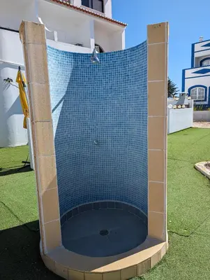 a shower with a blue tiled enclosure in a yard at Apartamento da Praia in Sagres