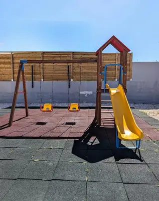 a playground with a yellow slide and a wooden fence at Apartamento da Praia in Sagres