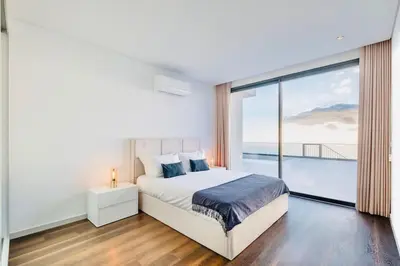 a white bedroom with a bed and a large window at Vila Cales e Chadas by Your Madeira Rentals in Arco da Calheta