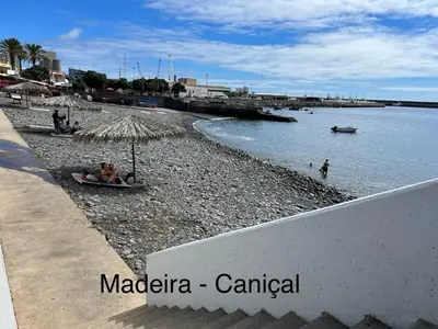 a table with chairs and an umbrella in front of a building at Caniçal houses - Madeira in Caniçal