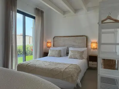 a white bedroom with a bed and a window at Casa Ingrina in Carrapateira