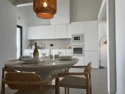 a white kitchen with a table with wine glasses at Casa Ingrina in Carrapateira