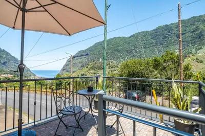 a balcony with an umbrella and a table and chairs at Colinas by Homie in São Vicente