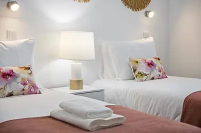 two beds in a white room with towels on them at Colinas by Homie in São Vicente