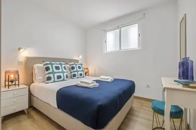 a bedroom with a bed with blue sheets and a desk at Colinas by Homie in São Vicente