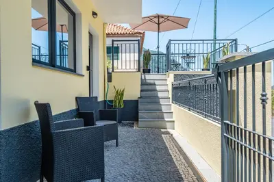 a balcony of a house with chairs and an umbrella at Colinas by Homie in São Vicente