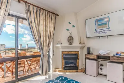 a living room with a fireplace and a balcony at Vila Luz Mar in Luz
