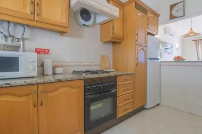 a kitchen with wooden cabinets and a stove and a microwave at Vila Luz Mar in Luz