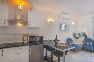 a kitchen with a table with a microwave and blue chairs at Vila Luz Mar in Luz