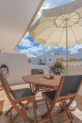 a wooden table and chairs with an umbrella on a balcony at Vila Luz Mar in Luz