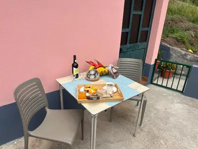 a table with a bottle of wine and a chair at Casa Rosa in Ribeira Brava