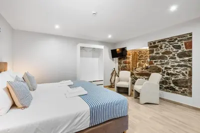 a bedroom with a bed with two chairs and a television at Seaside Sunset by Homie in Paul do Mar