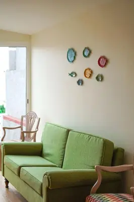 a living room with a green couch and plates on the wall at Renovated Traditional House w 3BR & Outdoor Space in Funchal