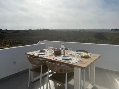 a table on a balcony with a view at Casa Zavial in Carrapateira