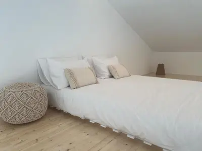 a white bed with white pillows and a stool at Casa Zavial in Carrapateira