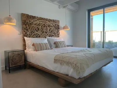 a bedroom with a large bed with a wooden headboard at Casa Barranco in Carrapateira