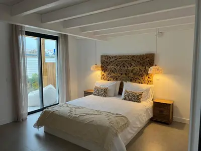 a bedroom with a bed and a large window at Casa Furnas in Carrapateira