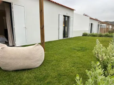 a large pillow sitting on the grass near a house at Casa Furnas in Carrapateira
