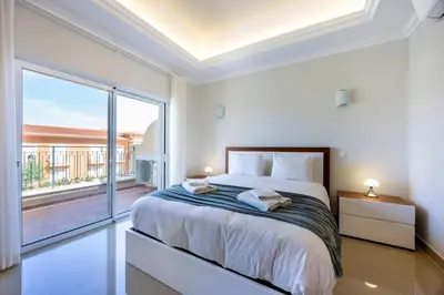 a bedroom with a large bed and a large window at Boa Vista - Casa Jacques in Lagos