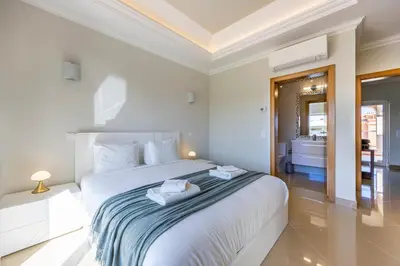a white bedroom with a bed with towels on it at Boa Vista - Casa Jacques in Lagos
