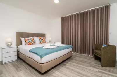 a white bedroom with a bed and a chair at Casa Antonette, Lovely house with a pool in Calheta