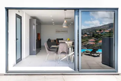 a living room with sliding glass doors and a dining room at Casa Antonette, Lovely house with a pool in Calheta